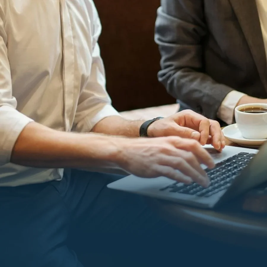 Two employees working with an open laptop.