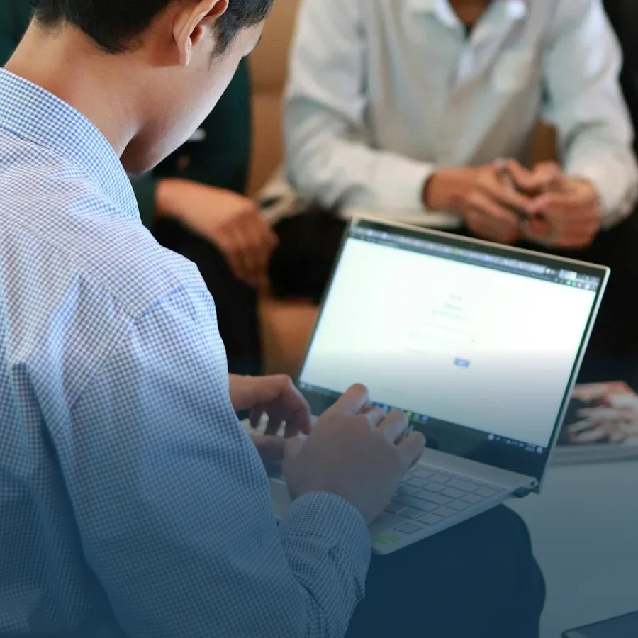 Two employees in a meeting discussing with an open laptop.