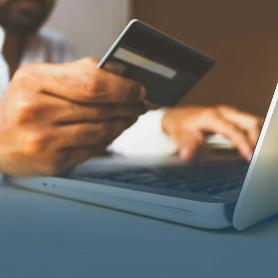 A person executing a payment from their bank account with a credit or debit card and laptop.
